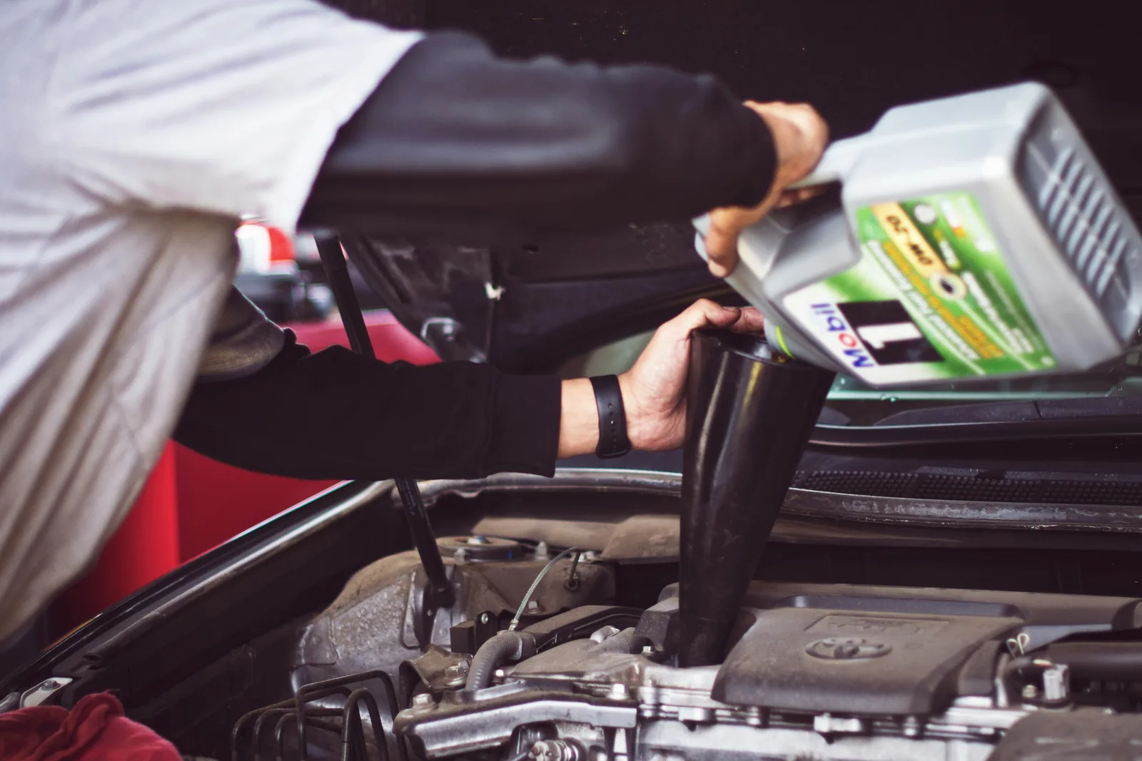 Technician adding motor oil during an oil change